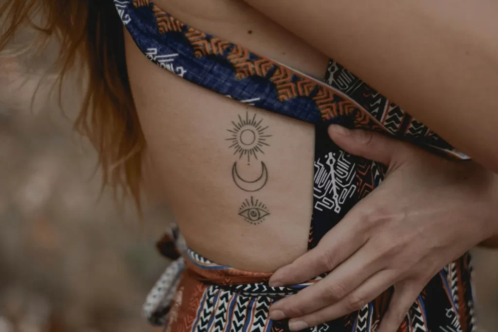Mujer con tatuajes populares de sol, luna y ojo